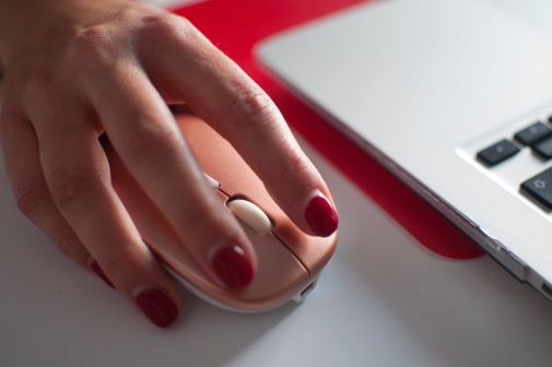 A woman's hand rests over a computer mouse.