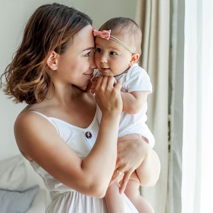 Young happy mother with her daughters in the home interior. Mothers Day. Cozy.