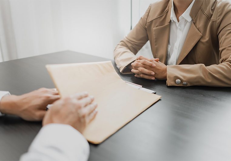 Two women sit at a table to review legal documents.