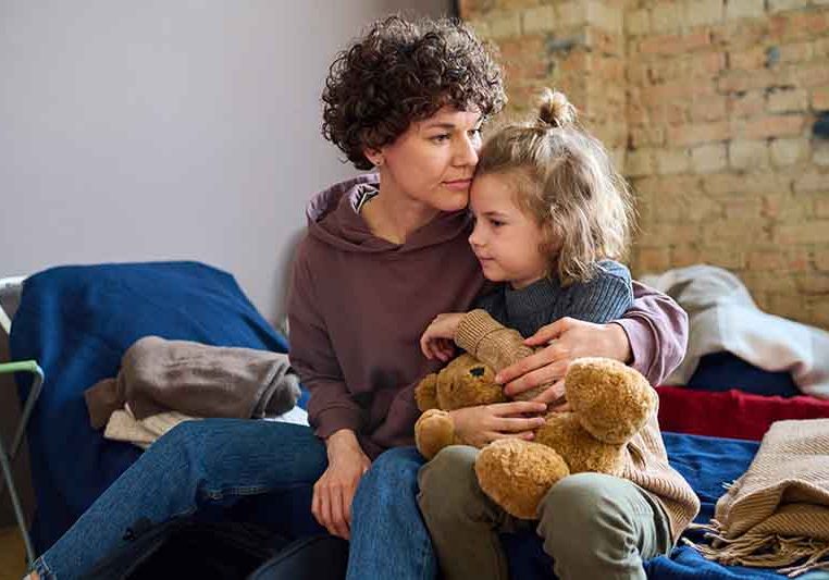 A woman hugs her young daughter at a domestic violence shelter.